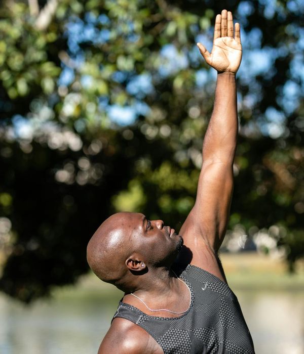 Man performing a dynamic stretching exercise in a bright room.